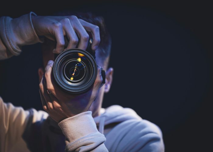 A man photographer with a camera takes a photo in the dark, copy space.