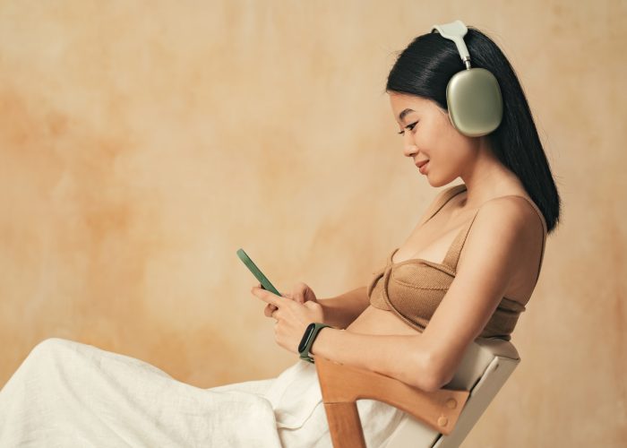 Side view of asian millennial girl in headphones video chatting with her boyfriend using phone app